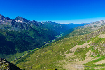Naklejka premium Landscape mountain view peaks in snow and green hills, deep blue sky and huge white clouds background, Hohe Tauern Austrian Alps, Europe
