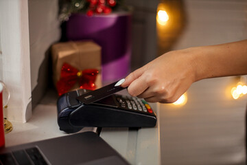 Customer is paying with card in christmas shop using NFC technology. NFC technology. Customer is paying