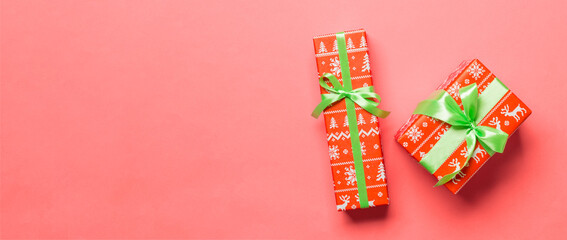 Fototapeta na wymiar Gift box with green bow for Christmas or New Year day on living coral background, top view