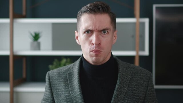 Close up angry businessman shouting and pointing at camera. Portrait of aggresive boss scolding and shouting at employees threatening with a finger and shouting at at office