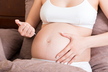 Fototapeta na wymiar Pregnant woman with insulin syringe in home on bed. Pregnant diabetes concept