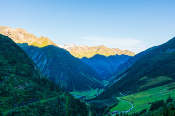 Fototapeta na wymiar Panoramic view with sunrise on idyllic mountain backdrop in the Alps with fresh green meadows in summer Stange near Zillergrundl. Austria Zillertaler Alpen tirol