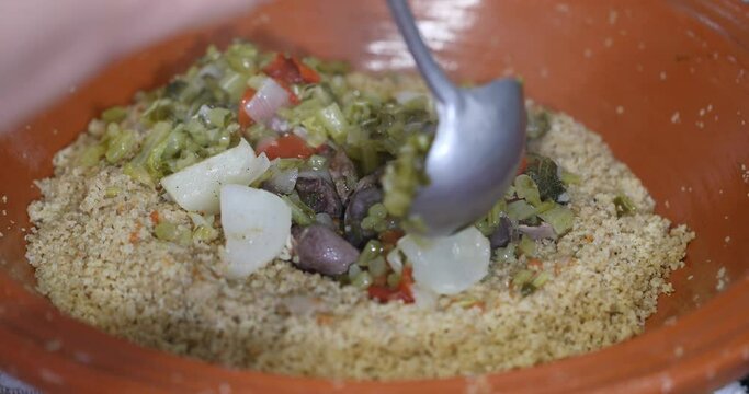 Preparing couscous with chicken offal and turnips and turnip greens in the large brown clay earthenware dish