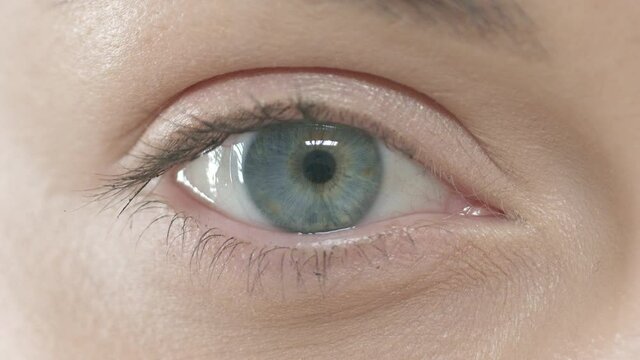 Close up slow motion of macro blue eye of young woman