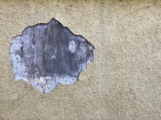 a concrete wall with a missing fragment of shattered paint, a wall of cement with a piece of paint fallen out