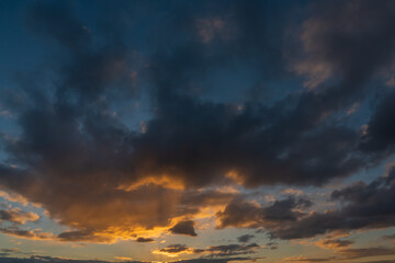 Dramatic sunset sky, orange and dark clouds.