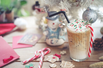 Festive drink. Merry Christmas with signature iced cinnamon coffee drink. candy canes and ginger breads on the wooden table. Soft focus and vintage filter.