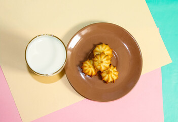 A glass of milk and homemade shortbread on a brown saucer. Delicious breakfast.