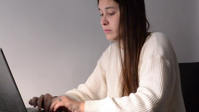 mujer de pelo negro trabajando en casa con ordenador portátil