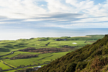 Looking over the green coast line around Gutterby and the Isle of Man beyond the Irish Sea, from the middle of Black Combe in the western Lake District National Park in England.