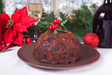 Fototapeta na wymiar Traditional Christmas pudding with holly on top on the wooden background.