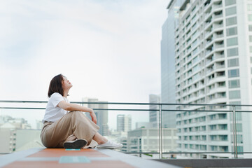 Fototapeta na wymiar solo asian woman sit and breatheduring outdoor break and relax at rooftop with city background