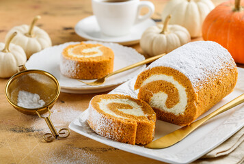 Obraz na płótnie Canvas Pumpkin roll cake with cream cheese and tea. Autumn dessert. Selective focus.