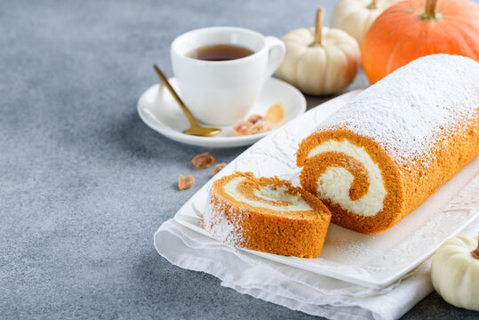 Pumpkin roll cake on a white plate. Autumn dessert. Copy space. Selective focus