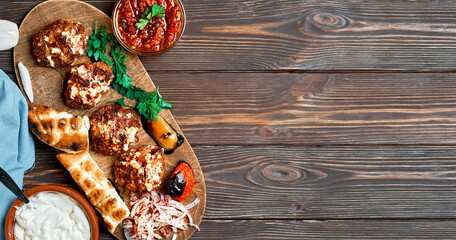 Fried meat. Meat balls or cutlets - Turkish kofte made from lamb and beef with cheese and spices. On a wooden platter with grilled vegetables, herbs and sauce. Layout with copy space