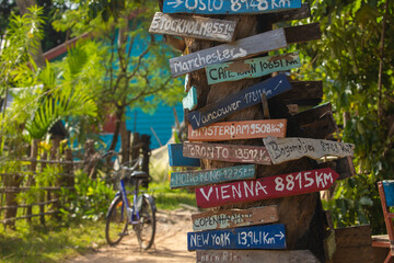 Colourful hand painted direction wood signs to different cities of the world, and mileage marker in Don Det island, one of the famous Four Thousand Islands or Si Phan Don, in the Mekong river, Laos.