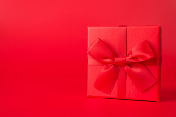 Surprise concept. Close up photo of red giftbox with red ribbon isolated on red background with copyspace