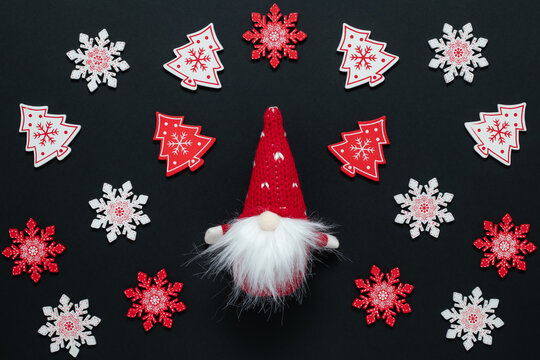 Christmas Ornament Pattern. Greeting Card With Santa Claus. New Year Decor On Black Background. Small Textile Gnome In Red Cap With Beard On Wallpaper With Red And White Snowflakes. Festive Design.