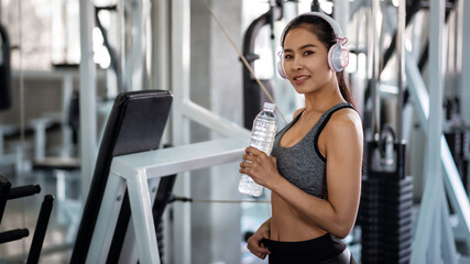 Fitness woman listen music and drink water in gym