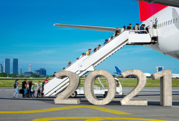 2021 3D text in the apron while People are boarding from the apron, by the stairs. Background city view.