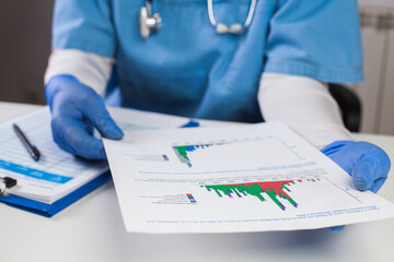 Doctor wearing protective gloves holding document chart,analyzing COVID-19 graph data,Coronavirus...