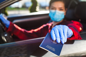 Young woman holding blue passport through car window,patrol border security staff checkpoint...