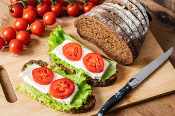 sandwich with cheese, lettuce and tomato on a wooden table