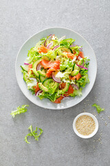 Salmon avocado salad with salted fish, fresh lettuce and red onion