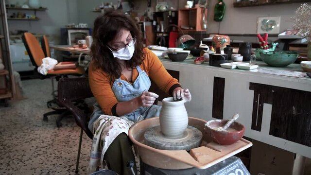 Mujer en estudio en un magistral trabajo de alfarería con arcilla en un torno de alfarero hecho a mano