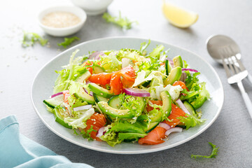 Salmon avocado salad with salted fish, fresh lettuce and red onion