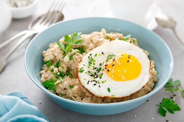 Savoury oatmeal with fried eggs sunny side up for breakfast