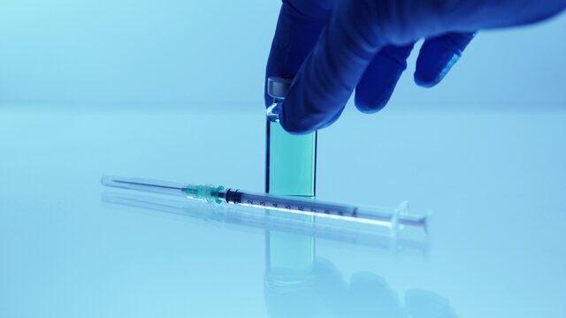 Medical vaccine scientist holding the glass vial with vaccine. Concept of developing research of vaccine against Coronavirus, COVID-19. Pre-clinical evaluation, clinical phase trials development test.