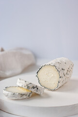 Delicious goat chevre cheese slices on a white wooden background.