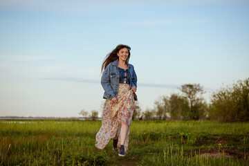 Happy cheerful young woman running across the field