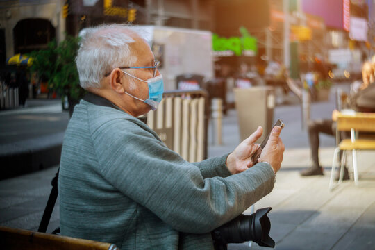 People wearing protective face masks outdoors due to coronavirus epidemic on man with his smartphone in New York