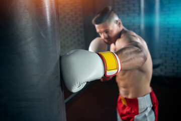 close up of muscular boxer male training with punching bag in gym