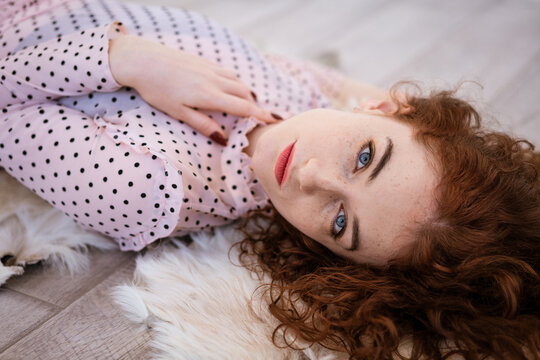 Portrait of a beautiful red-haired woman lying on the floor