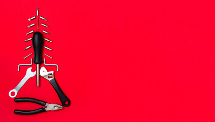Creative christmas tree on red background, made of tools. Set of construction tools on xmas backdrop. Industrial greeting card. Christmas and happy new year concept. Flatlay with space for text.