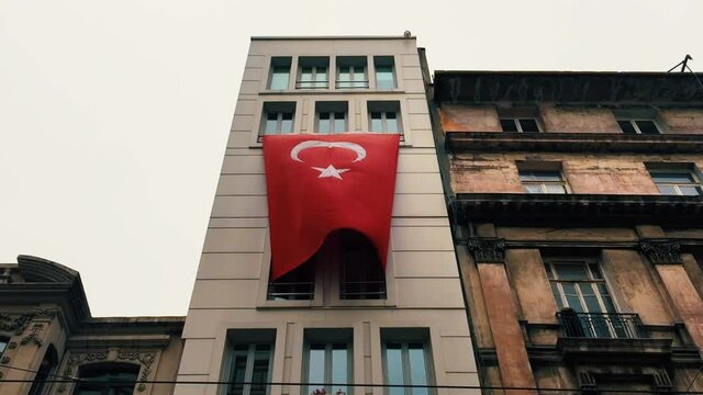 Huge national flag of Turkey on building exterior in center of Istanbul in tourist district of Taksim filmed in spring season