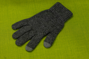 Winter grey glove on a green background.