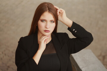 Beautiful young girl in a fashionable black dress and a long coat.