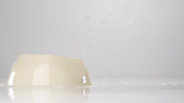 Creamy jelly falling down. Falling jelly on white wet surface in slow motion.