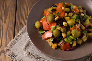 Traditional Sicilian dish of eggplant caponata on a wooden table. Top view