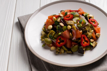 Traditional Sicilian dish of eggplant caponata, in a plate, on a wooden table