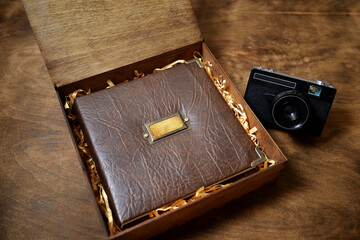 gift photo book in a leather cover in a wooden box on a wooded background. Vintage photo album.