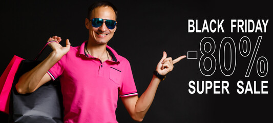 Handsome man holding pile of paper bags showing inscription black friday. Black friday concept