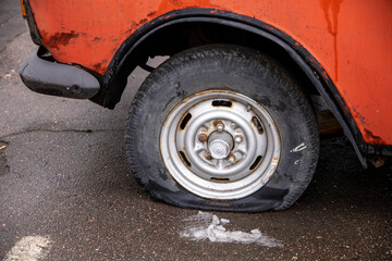 Deflated damaged tire on the wheel of an old car - obrazy, fototapety, plakaty