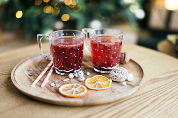 Hot Christmas tea or mulled wine on a wooden tray with orange and new years decor on the background...