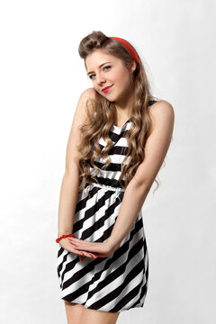Portrait of a girl in pin-up style. Girl with a watch, in a striped dress on a white background. Red bow.