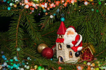 Santa Claus on a house near the branches of a Christmas tree. Background for New Year and Christmas.